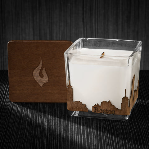 Image of a 3x3x3 soy candle featuring a mahogany scent, crackling wood wick, with a wood lid and an Boston skyline wrap design.