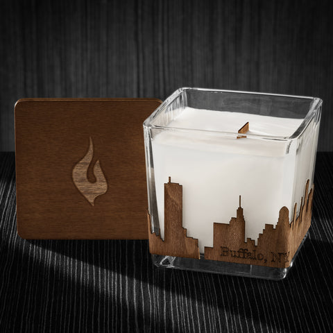 Image of a 4x4x4 soy candle featuring a mahogany scent, crackling wood wick, with a wood lid and an Buffalo, NY skyline wrap design.