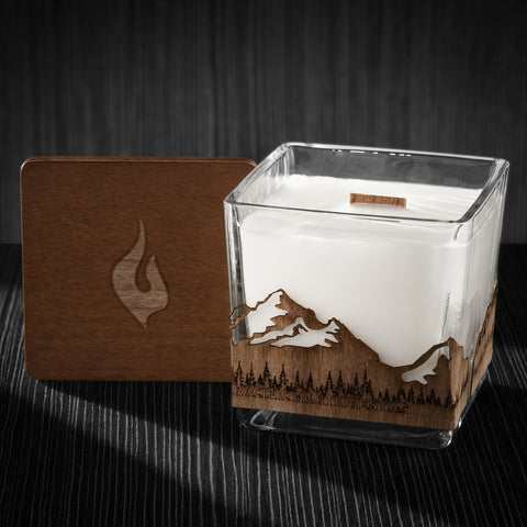 Image of a 3x3x3 soy candle featuring a mahogany scent, crackling wood wick, with a wood lid and a Pacific Northwest skyline wrap design.