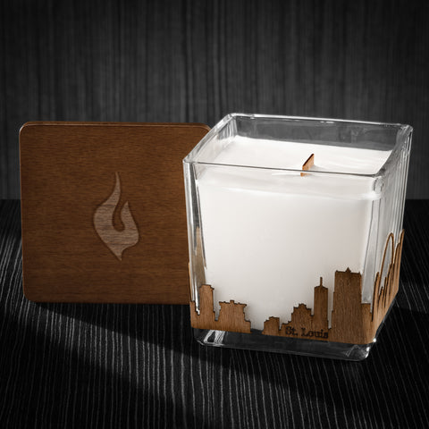 Image of a 3x3x3 soy candle featuring a mahogany scent, crackling wood wick, with a wood lid and a St. Louis skyline wrap design.